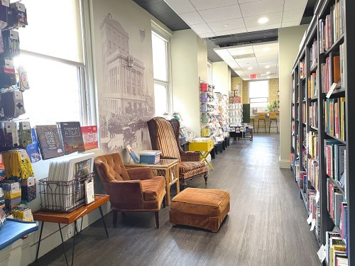A cozy library corridor with bookshelves, seating, and a mural, creating a welcoming reading space.