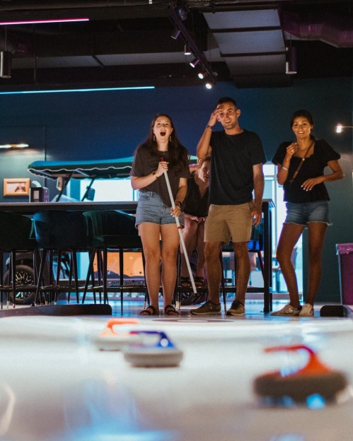A group of friends enjoying a game in a vibrant, modern arcade setting, laughing and having fun together.