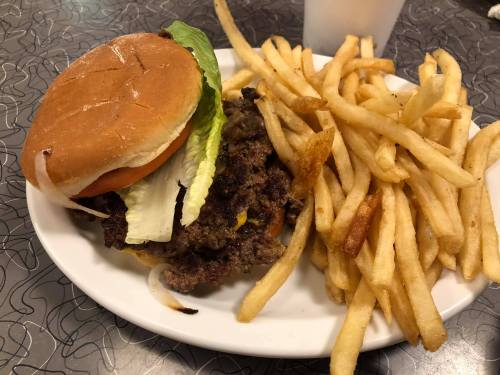 A plate with a cheeseburger topped with lettuce and tomato, accompanied by a side of golden French fries.