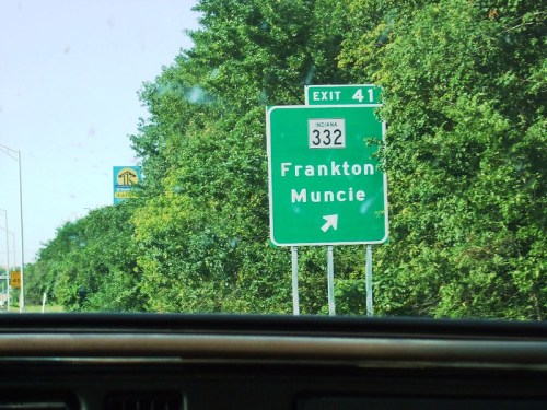 Green highway sign indicating Exit 41 for Frankton and Muncie, with a right arrow, surrounded by trees.