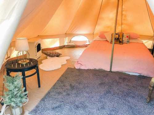 Cozy glamping tent interior with a bed, side table, rug, and decorative elements. Warm and inviting atmosphere.