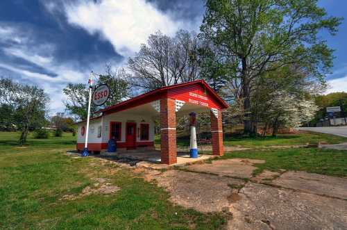 Vintage Esso gas station with red and white exterior, surrounded by trees and a cloudy sky.