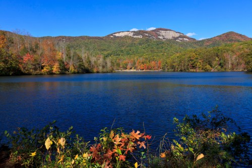 A serene lake surrounded by colorful autumn foliage and mountains under a clear blue sky.