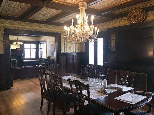 Elegant dining room featuring a chandelier, wooden furniture, and intricate ceiling details.