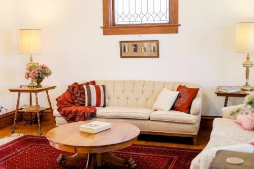 Cozy living room with a tufted beige sofa, round wooden coffee table, floral arrangements, and warm lighting.