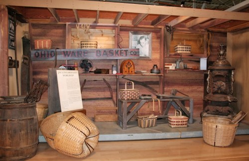 Display of vintage baskets and tools in a rustic workshop setting, showcasing Ohio Ware Basket Co. artifacts.