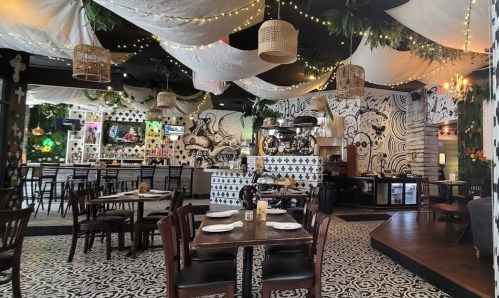 A vibrant restaurant interior with decorative lighting, patterned floors, and a cozy seating arrangement.