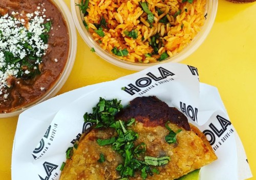A plate featuring a crispy taco topped with cilantro, alongside rice and beans in bowls, all on a bright yellow background.