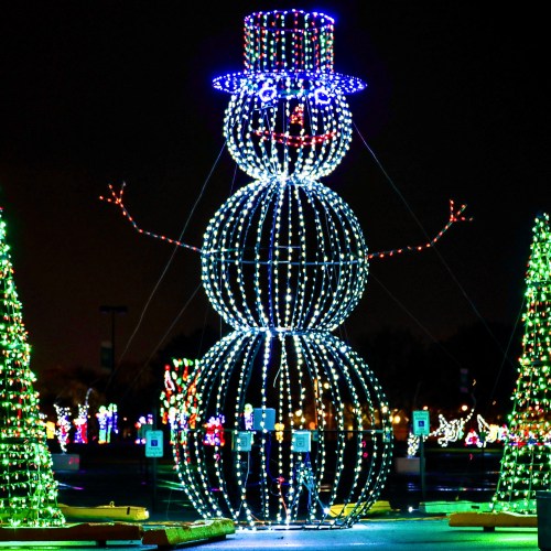 A large, illuminated snowman with a top hat, surrounded by colorful holiday lights and trees.