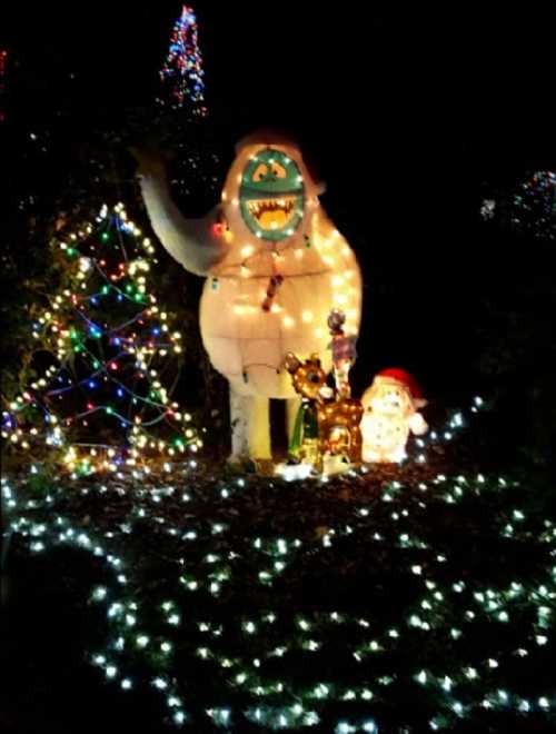 A festive scene featuring a large, illuminated yeti, a decorated Christmas tree, and cheerful holiday decorations.