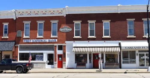 A row of brick buildings featuring a bank, a restaurant, and a funeral home, with a parked truck in front.