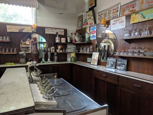 Vintage ice cream shop interior with mirrors, glassware, and retro signage, showcasing a nostalgic atmosphere.
