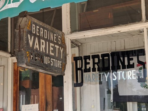 Sign for Berdine's Variety Store, featuring vintage lettering and a rustic storefront.
