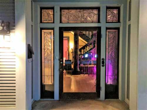 A decorative entrance with stained glass, revealing a glimpse of a colorful interior and staircase beyond.