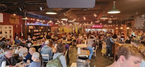 A bustling restaurant filled with people dining, chatting, and enjoying a lively atmosphere under warm lighting.