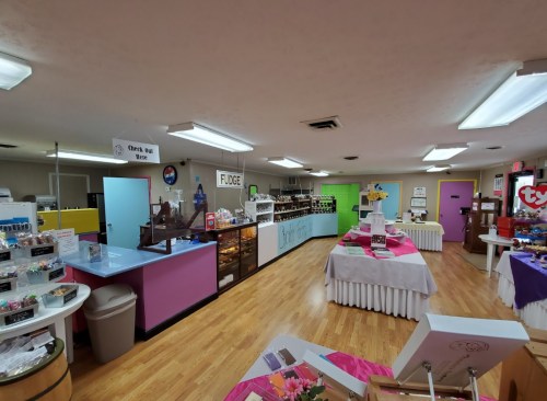 Interior of a colorful candy shop with display counters, tables, and a variety of sweets on display.