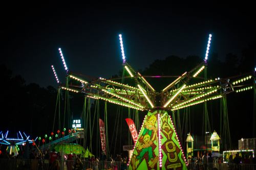 A brightly lit carnival ride at night, surrounded by colorful lights and festive decorations.