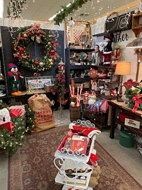 A cozy holiday display featuring decorations, a wreath, gifts, and festive items in a charming shop setting.