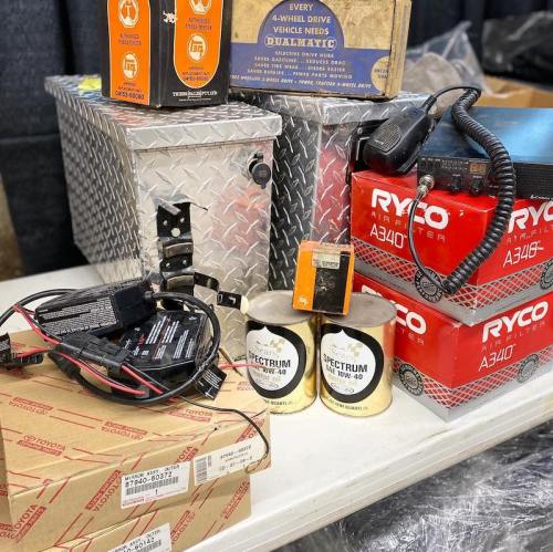A collection of automotive parts and accessories, including batteries, boxes, and wiring components on a table.