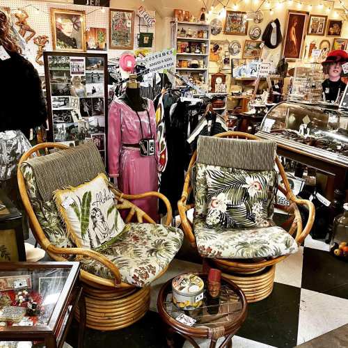 A cozy vintage shop filled with eclectic decor, furniture, and a friendly shopkeeper in the background.