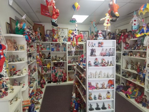 A colorful room filled with shelves of various clown figurines and dolls, creating a whimsical atmosphere.