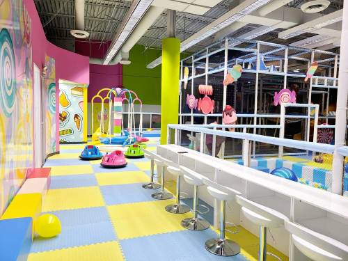 Brightly colored indoor play area with bumper cars, soft flooring, and playful decorations.