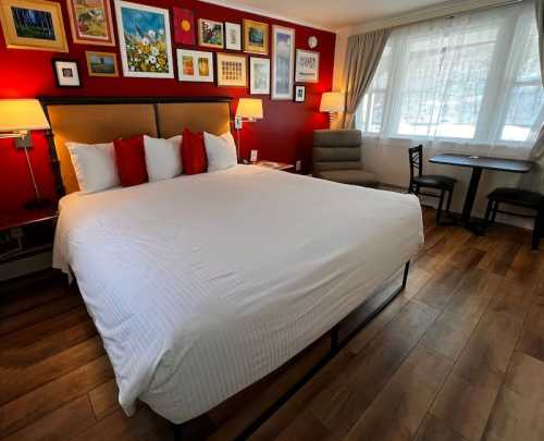 Cozy hotel room featuring a large bed, artwork on the walls, and a seating area with a table and chair.