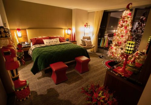 A festive bedroom decorated for the holidays, featuring a Christmas tree, nutcracker figures, and cozy green bedding.