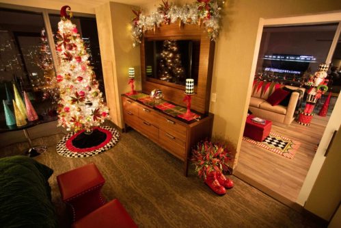 A festive room decorated for the holidays, featuring a lit Christmas tree, colorful ornaments, and vibrant decor.