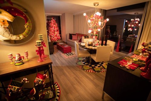 A festive living room decorated for the holidays, featuring a Christmas tree, colorful ornaments, and cheerful table settings.