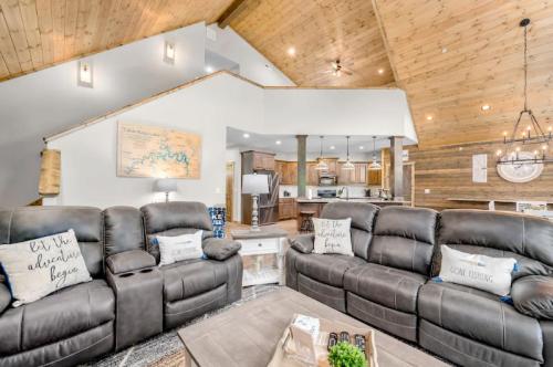 Cozy living room with dark leather sofas, wooden ceiling, and a view of the kitchen and dining area.