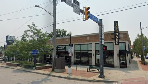 A street view of a corner building featuring "Landmark" signage, with trees and traffic signals nearby.