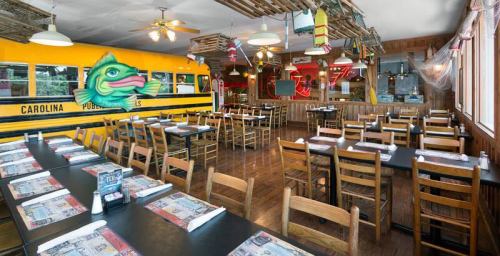 Interior of a quirky restaurant featuring wooden tables, chairs, and a colorful bus mural. Bright and inviting atmosphere.