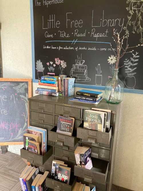 A cozy Little Free Library with shelves of books, a chalkboard sign, and a welcoming atmosphere.