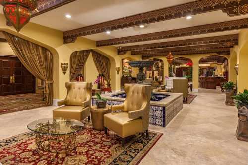 Luxurious lobby with ornate decor, plush seating, a fountain, and warm lighting, creating an inviting atmosphere.