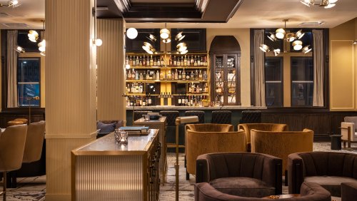 Elegant bar interior featuring a well-stocked shelf, stylish seating, and modern lighting fixtures.