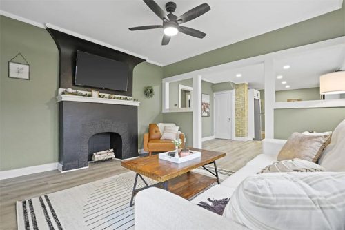 Cozy living room with green walls, a black fireplace, a wooden coffee table, and modern decor.