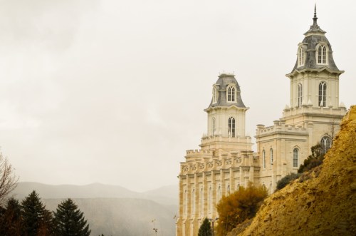 A grand building with two tall towers, set against a misty landscape and mountains in the background.