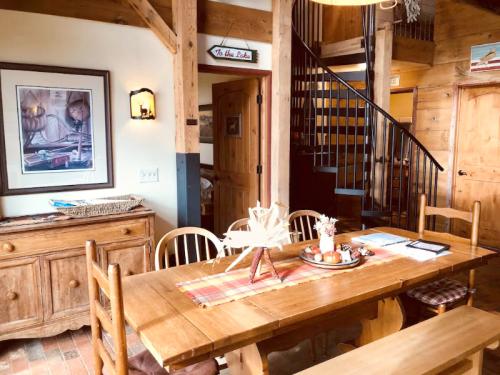 Cozy dining area with a wooden table, chairs, and rustic decor, featuring a staircase and warm lighting.