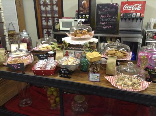 A display of assorted baked goods in glass containers, including cookies, pastries, and candies, on a rustic table.