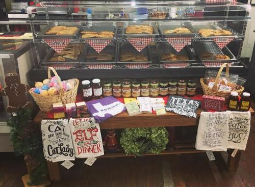 A display of baked goods, jars, and festive items on a wooden table, with decorative towels and a wreath.