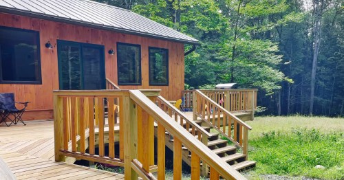 a modern cabin with a deck in the woods in massachusetts