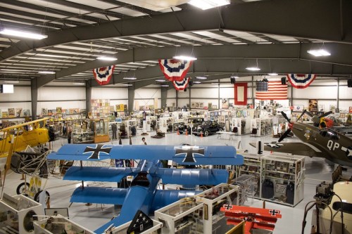 A spacious aviation museum featuring vintage aircraft, military memorabilia, and patriotic decorations.