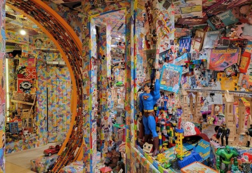 A vibrant room filled with colorful toys, posters, and memorabilia, creating a whimsical, nostalgic atmosphere.