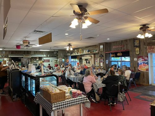A cozy diner filled with patrons at checkered tables, featuring a warm atmosphere and vintage decor.