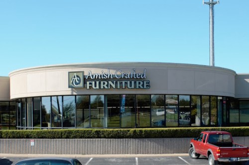 Exterior of a furniture store with a sign reading "Amish Crafted Furniture" and a red truck parked outside.