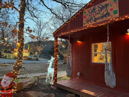 A cozy gift shop decorated with lights, featuring a Santa figure and a glowing reindeer in a festive outdoor setting.