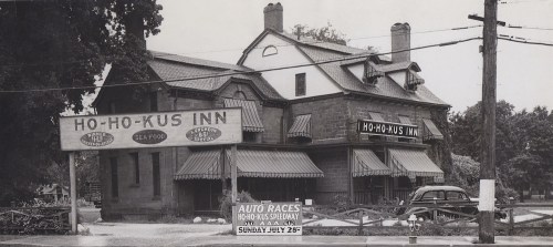 Historic photo of Ho-Ho-Kus Inn, featuring signage for seafood and auto races, surrounded by trees and power lines.
