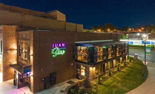 A vibrant restaurant named "Juan Sinas" illuminated at night, featuring large windows and outdoor seating.