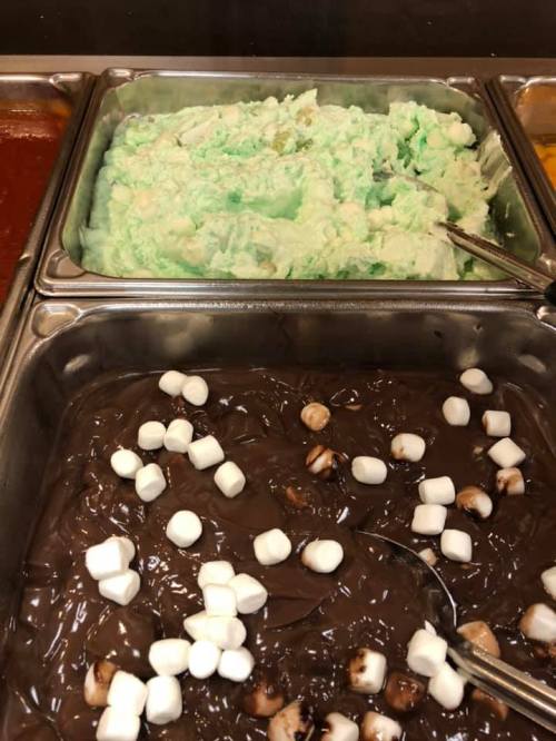 Two trays of dessert: one with green fluffy dessert and another with chocolate pudding topped with mini marshmallows.